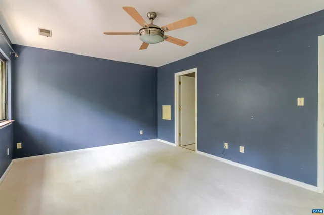 an empty room with ceiling fan and window