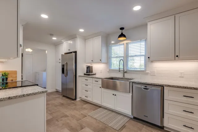a kitchen with granite countertop cabinets stainless steel appliances a sink and a window