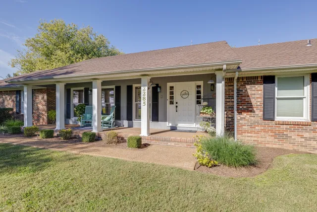 front view of a brick house with a large window and potted plants
