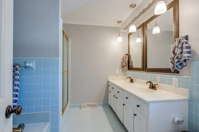 a bathroom with a double vanity sink mirror and shower