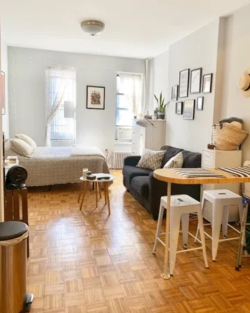 a living room with a couch and a dining table with wooden floor