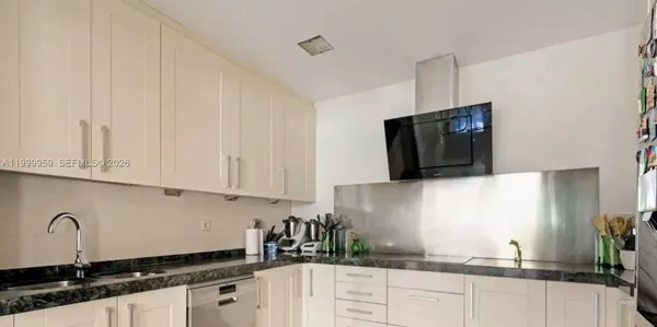 a kitchen with granite countertop white cabinets and black appliances