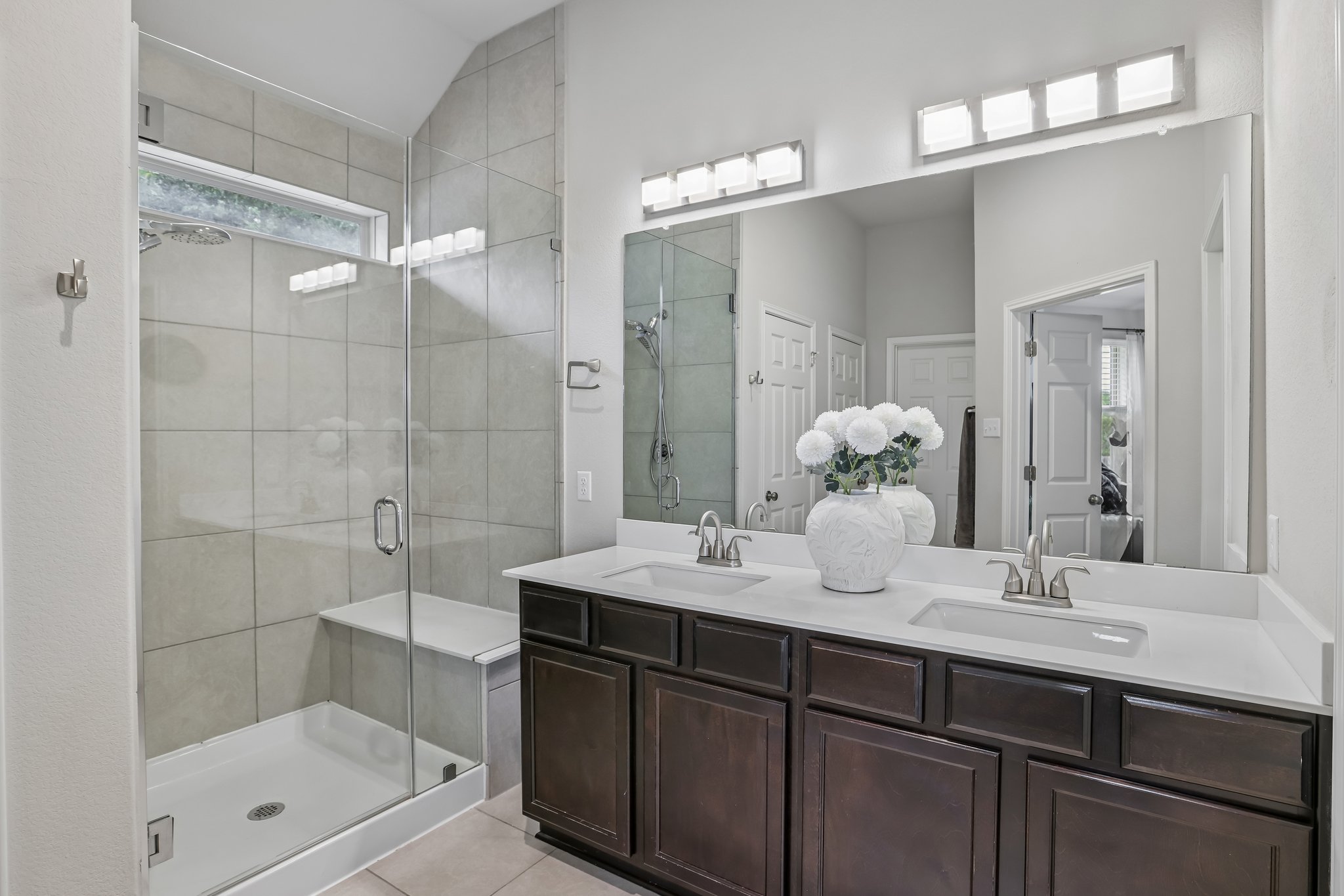 6801 Banff Cove Austin, TX 78754 - Photo 19 of 37 A well-lit primary bathroom featuring a spacious walk-in shower with bench and a dual-sink vanity