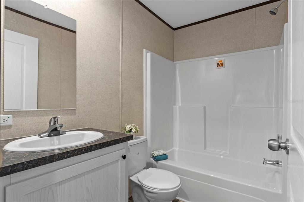 2455 East North Street Inverness, FL 34453 - Photo 23 of 27 a bathroom with a granite countertop sink a toilet and shower