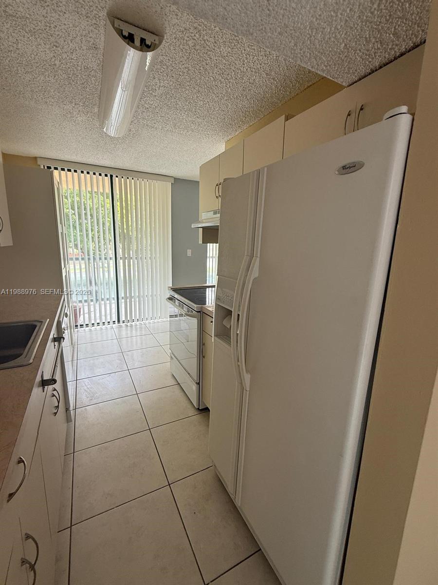 11780 Southwest 18th Street, Unit 2302 Miami, FL 33175 - Photo 6 of 15 a view of a refrigerator in kitchen and an empty room
