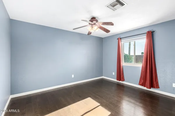 an empty room with wooden floor chandelier fan and windows