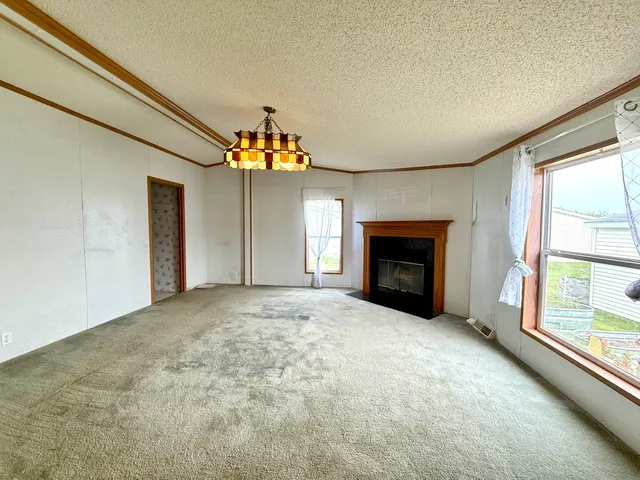 a view of an empty room with a fireplace and a window