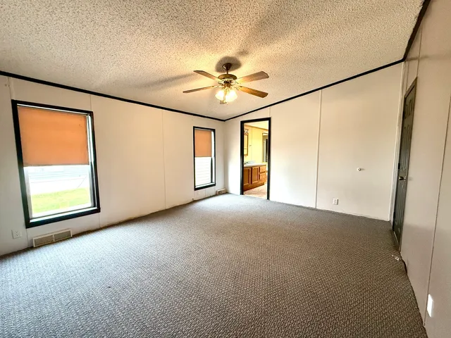 an empty room with windows and fan