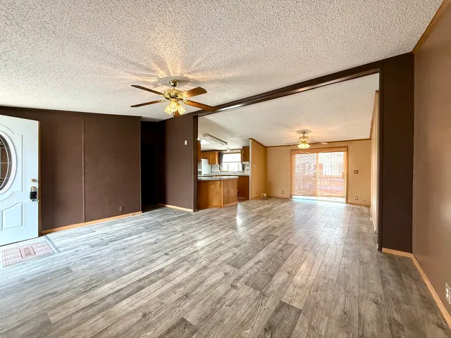 a view of an empty room with window and wooden floor