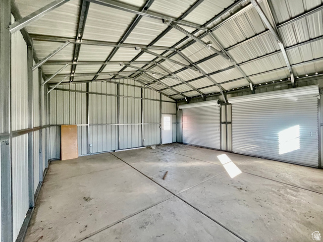 255 West Main Street Mount Pleasant, UT 84647 - Photo 29 of 35 Spacious metal building with a concrete floor, two roll-up doors, a side entry door, and exposed metal truss ceiling