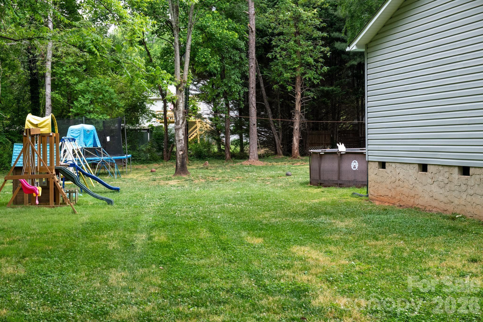 2308 Walt Arney Road Lenoir, NC 28645 - Photo 5 of 37 a view of a backyard with a slide trees and wooden fence
