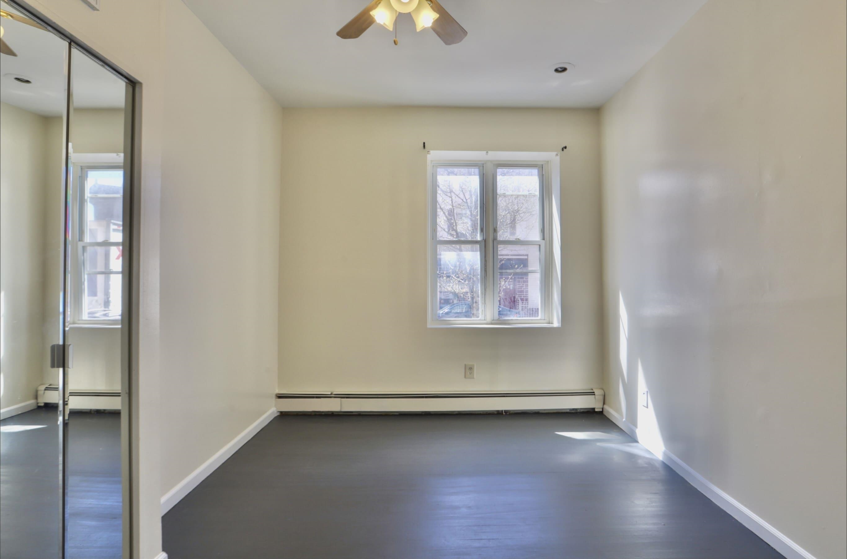314 Paterson Plank Road, Unit 1B Union City, NJ 07087 - Photo 8 of 22 an empty room with wooden floor and windows