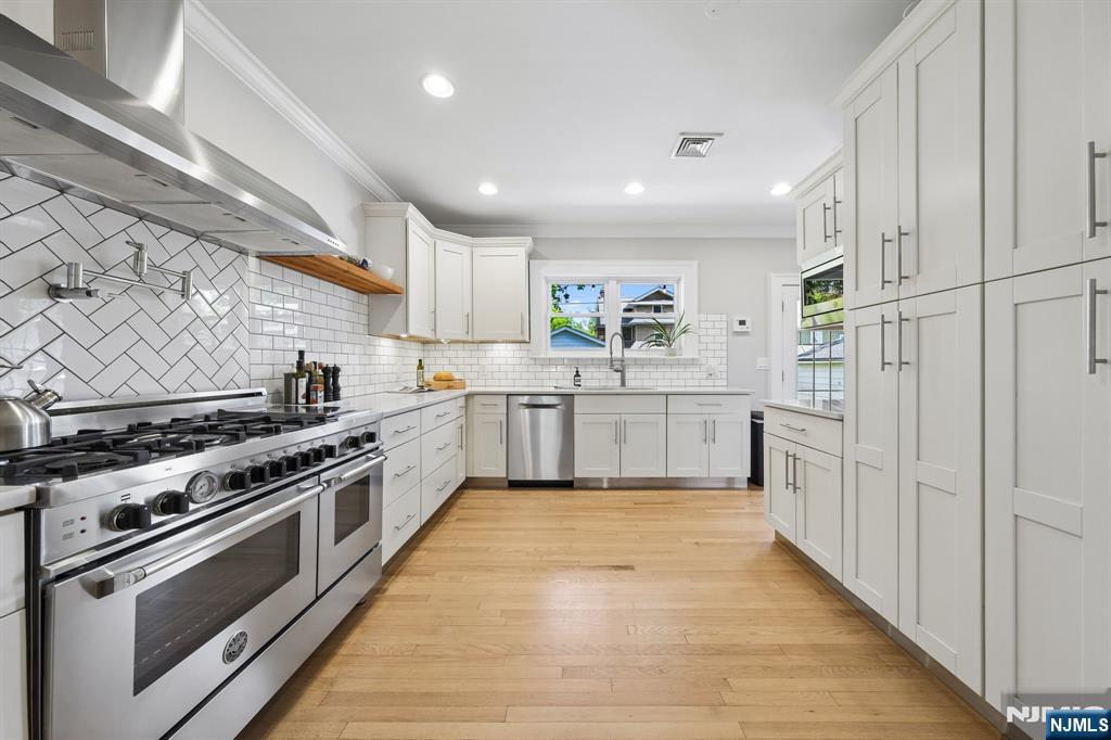 34 Prescott Avenue Montclair, NJ 07042 - Photo 9 of 40 a large kitchen with stainless steel appliances granite countertop a stove top oven a sink dishwasher and white cabinets with wooden floor