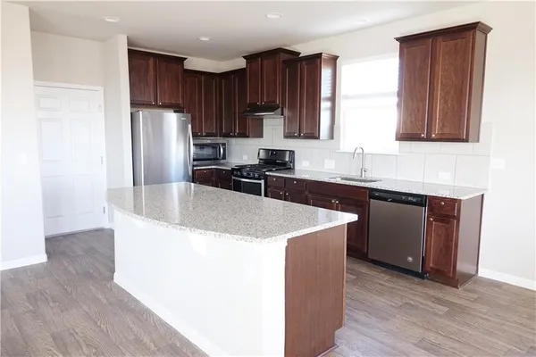 a kitchen with stainless steel appliances granite countertop a sink a refrigerator and a stove