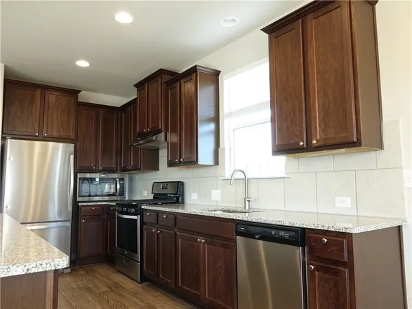 a kitchen with stainless steel appliances granite countertop a refrigerator stove a sink and dishwasher with wooden floor