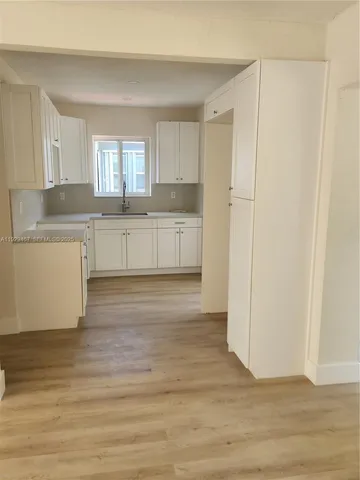 a kitchen with a refrigerator and white cabinets