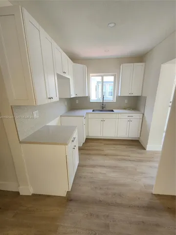 a large kitchen with a lot of counter space and wooden floor