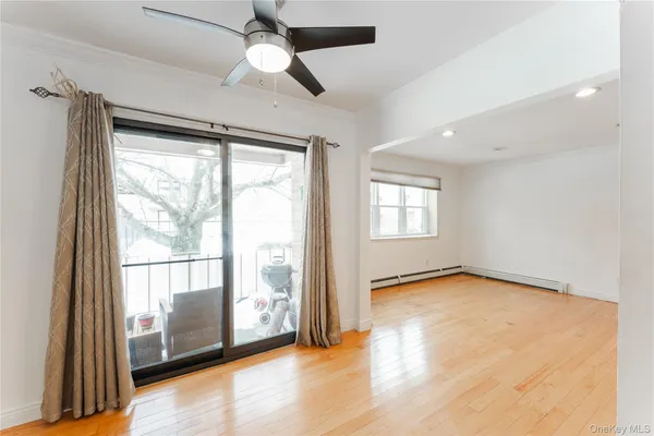 a view of an empty room with a window and wooden floor