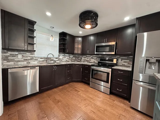 a kitchen with stainless steel appliances granite countertop a stove a sink dishwasher a refrigerator and a microwave