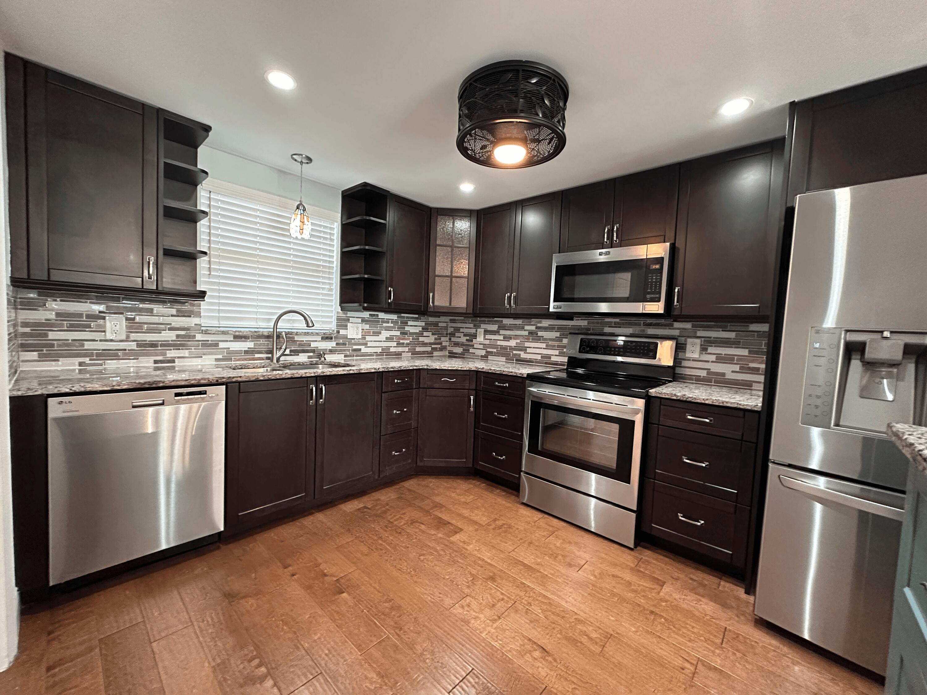 a kitchen with stainless steel appliances granite countertop a stove a sink dishwasher a refrigerator and a microwave