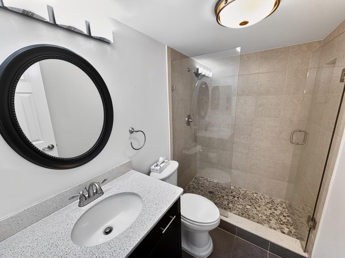 145 Atlantis Boulevard, Unit 302 Atlantis, FL 33462 - Photo 14 of 19 a bathroom with a sink a toilet and a mirror