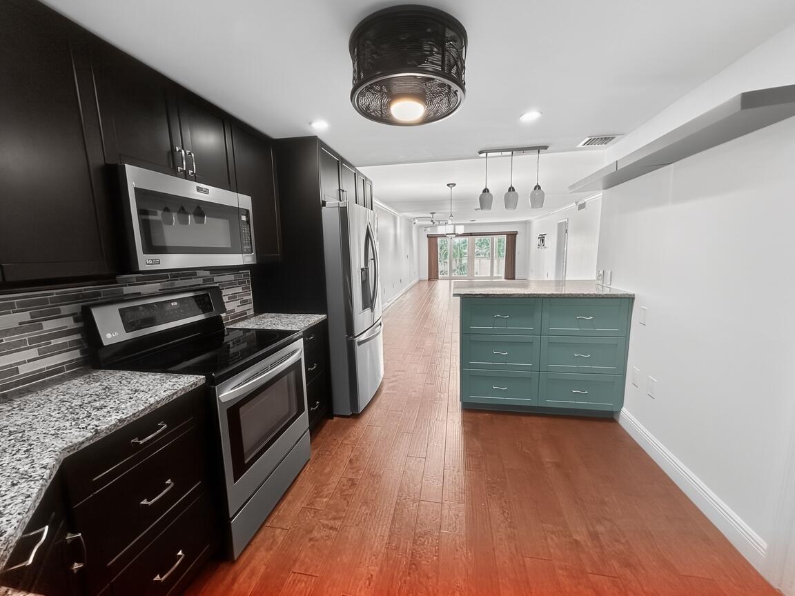 145 Atlantis Boulevard, Unit 302 Atlantis, FL 33462 - Photo 3 of 19 a kitchen with stainless steel appliances granite countertop a stove and a wooden floors