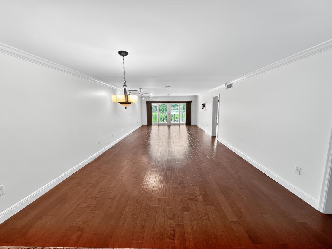 145 Atlantis Boulevard, Unit 302 Atlantis, FL 33462 - Photo 5 of 19 a view of empty room with wooden floor