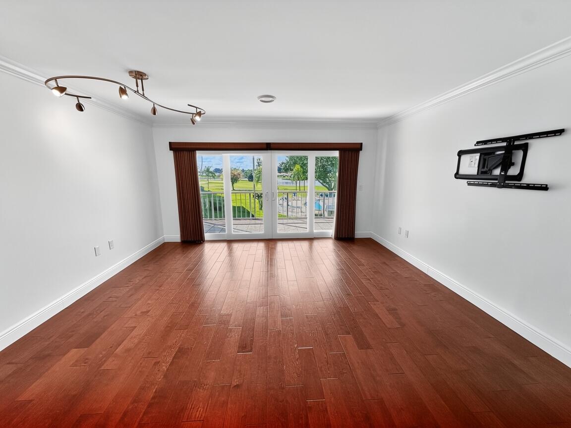 145 Atlantis Boulevard, Unit 302 Atlantis, FL 33462 - Photo 6 of 19 an empty room with wooden floor and windows