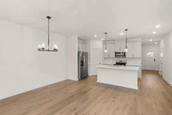 a view of a kitchen with stainless steel appliances granite countertop a refrigerator a stove top oven a sink and a wooden floor