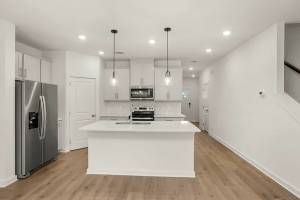a kitchen with kitchen island a refrigerator a sink and wooden floor
