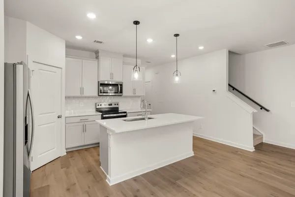 a kitchen with kitchen island a sink stainless steel appliances and wooden floor