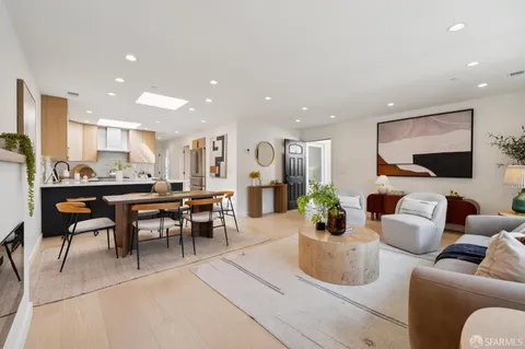 a kitchen with granite countertop a table chairs stove a sink and white cabinets with wooden floor