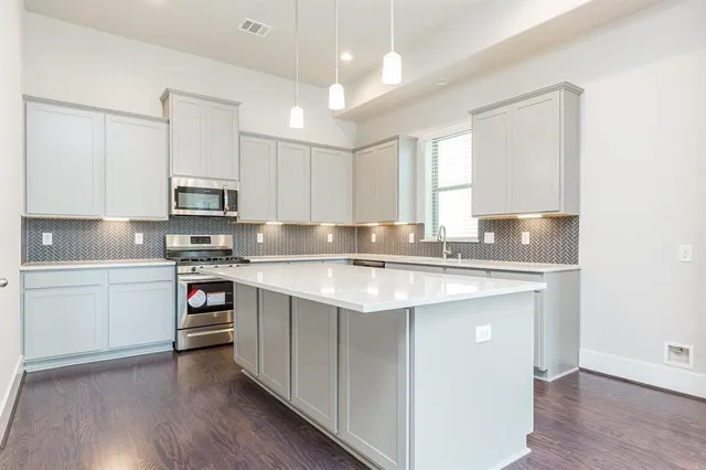 a kitchen with stainless steel appliances granite countertop a sink stove and white cabinets