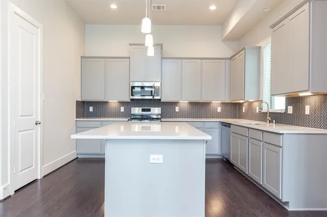 a kitchen with kitchen island granite countertop a sink a counter space appliances and cabinets