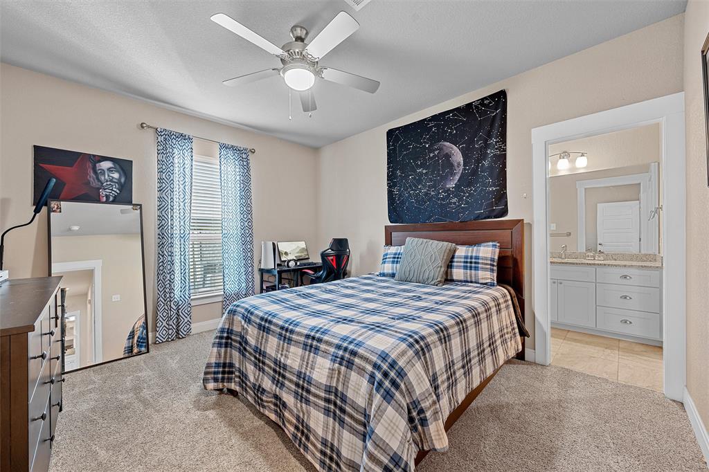 23 Independence Trail Waco, TX 76708 - Photo 26 of 35 Carpeted bedroom featuring a ceiling fan with integrated lighting, a window with blinds, and an open doorway revealing a bathroom with a vanity and tile flooring
