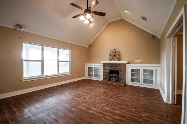 a view of an empty room with wooden floor fireplace and a window