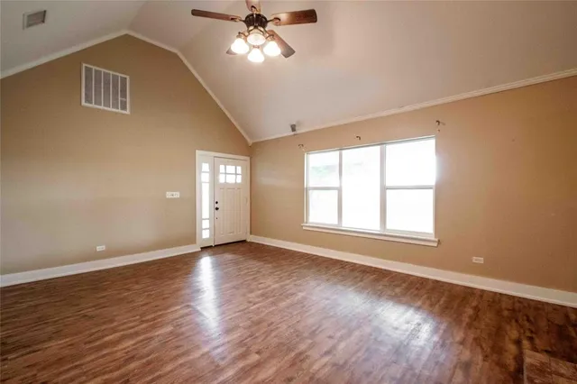 a view of an empty room with a window and wooden floor