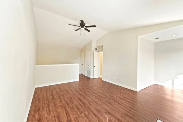 a view of empty room with wooden floor and fan