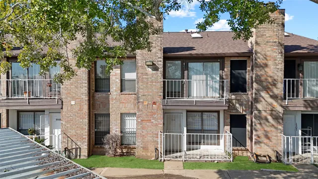 a view of a brick house with many windows and a large tree
