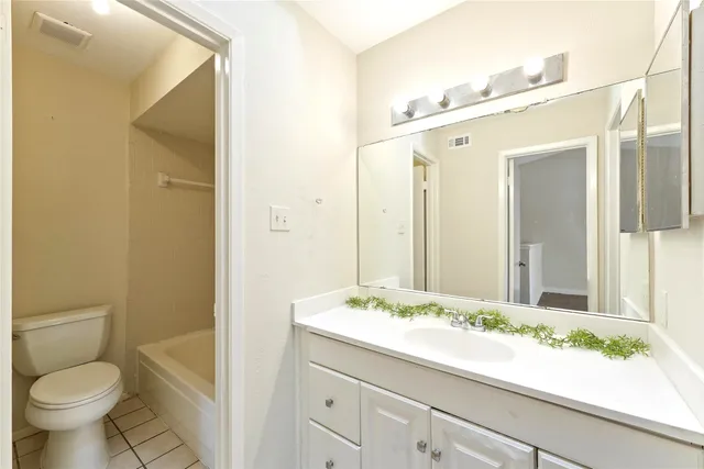 a bathroom with a granite countertop sink a toilet and a mirror