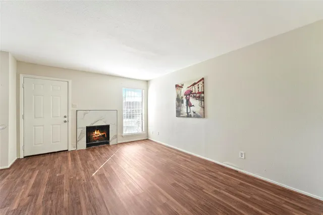 a view of empty room with wooden floor and fireplace