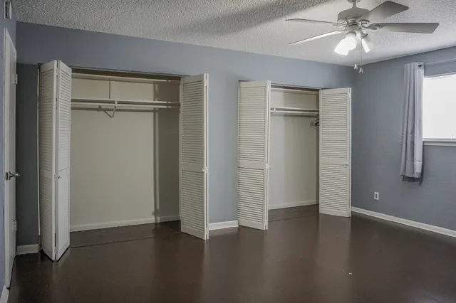 an empty room with wooden floor closet and windows