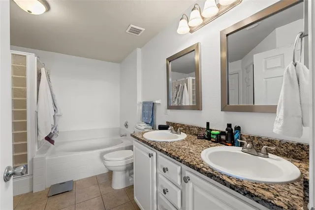 a bathroom with a granite countertop sink a toilet and a mirror