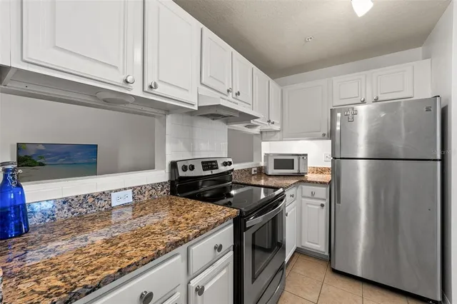 a kitchen with granite countertop white cabinets and a stove