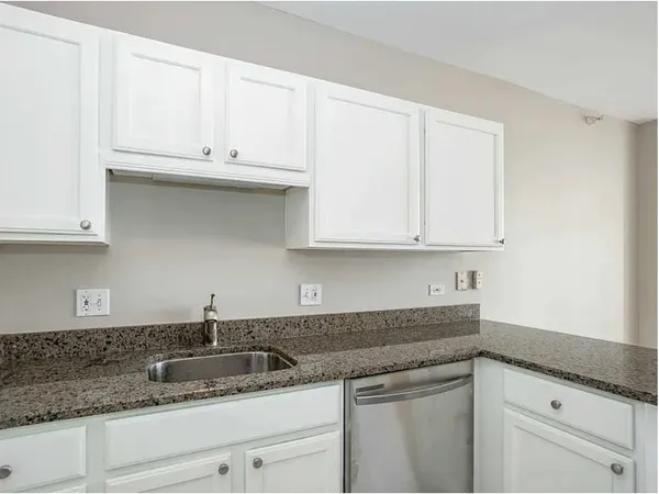 a kitchen with granite countertop white cabinets and a sink