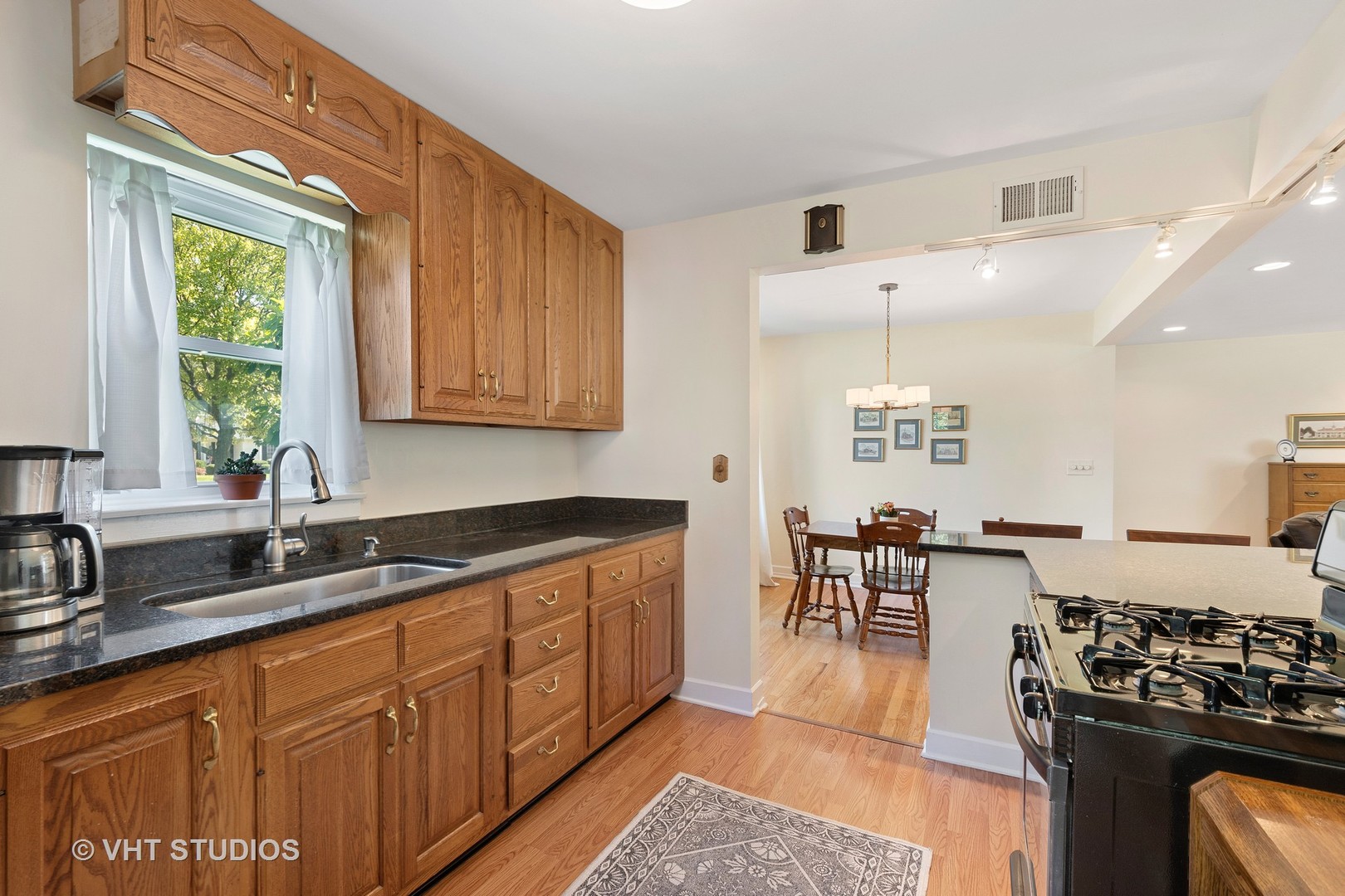 350 Wagner Road Northfield, IL 60093 - Photo 4 of 12 a kitchen with granite countertop a stove a sink a dining table and chairs