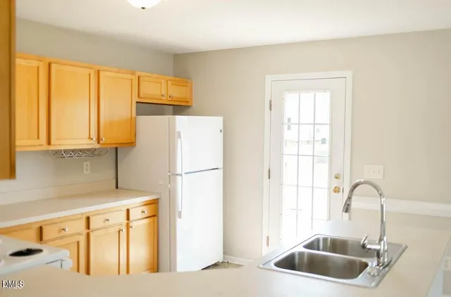 a kitchen with a sink a refrigerator and cabinets