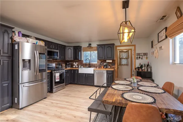a kitchen with stainless steel appliances kitchen island granite countertop a refrigerator a stove a sink dishwasher a dining table and chairs with wooden floor