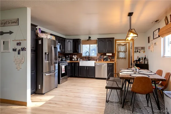 a kitchen view with stainless steel appliances kitchen island granite countertop a refrigerator a stove top oven a sink dishwasher and a dining table with wooden floor