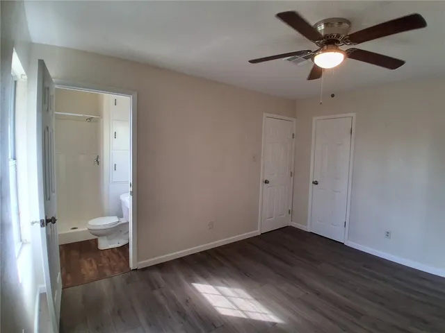 an empty room with wooden floor and a ceiling fan